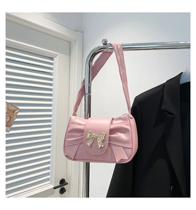 Detailed close-up of pink ruched hobo bag with gold metal bow and matte leather finish