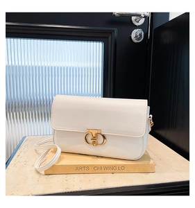 Close-up of cream PU leather handbag with elegant gold ring buckle on a book