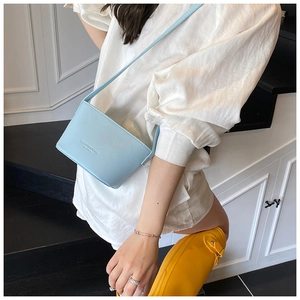 Detail of a light blue lychee pattern bucket bag with fashion lettering and slim strap