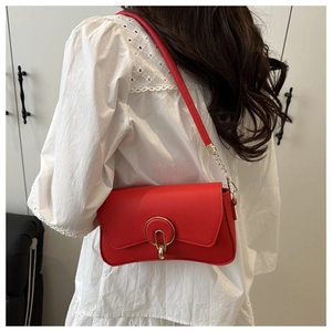 Macro detail of red leather handbag featuring a designer golden circular lock and U-pendant