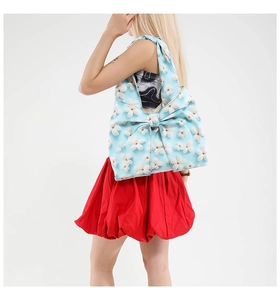 Floral light blue shoulder bag with a large bow design worn by a model in studio