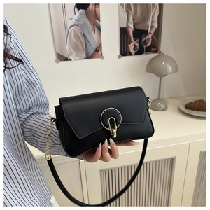 Detalle del bolso negro con hebilla de metal dorado y correa de cuero y cadena dorada