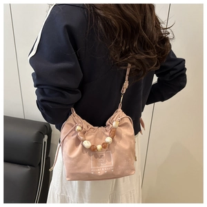Vue détaillée du sac à bandoulière rose en suédine avec poignée à perles marbrées