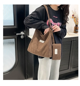 Brown corduroy tote bag with matching zipper pouch shown on person in modern interior