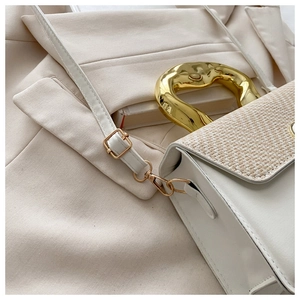 Close-up of woven flap texture and irregular gold metal handle on a chic white handbag