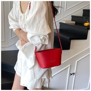 Close-up of litchi grain red bucket bag worn by a model on a crossbody leather strap
