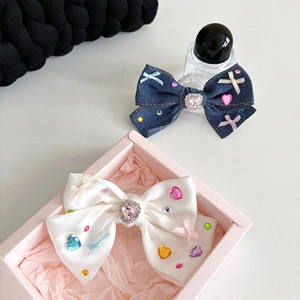 Close-up of denim and satin bow phone grips with pink heart rhinestones and colorful crystals