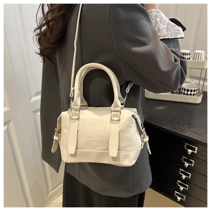 Détail du sac bandoulière blanc crème montrant le lettrage en relief et le cuir mat
