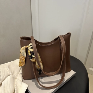 Brown leather tote bag with white stitching and decorative silk scarf on display