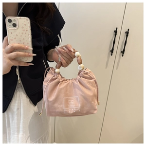 Detailed shot of pink drawstring beaded handbag with logo and premium beaded handle