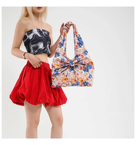 Floral tote bag featuring vibrant daisy patterns and a large 3D bow on the surface