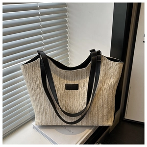 Detailed view of woven straw tote bag with V-shaped texture and black leather fashion label