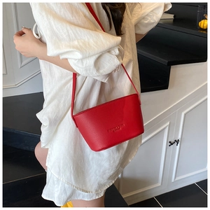 Detail view of red litchi texture bucket bag with embossed logo on shoulder strap