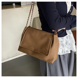 Detail of coffee-colored ribbed fabric crossbody bag with elegant chain shoulder strap