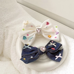 Detail of rhinestone bow phone socket with pink heart gem and satin denim fabric