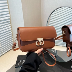 Brown faux leather crossbody bag with golden interlocking clasp shown in lifestyle setting