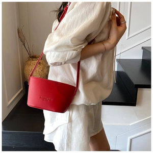 Detail of red lychee textured bucket bag with embossed logo and slim shoulder strap