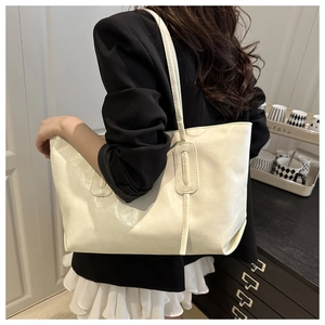 Detail view of the cream large tote bag showing shiny PU leather texture and reinforced stitching