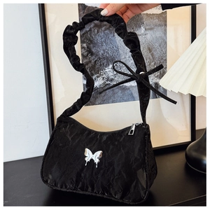 Detail of black pleated underarm bag with silver butterfly buckle and ruched strap