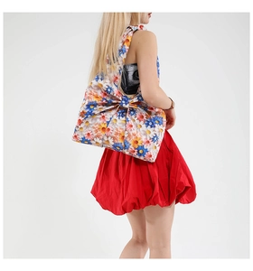 Detail of oversized bow shoulder bag with vibrant daisy print on a standing model