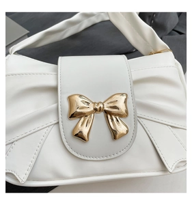 Detailed close-up of white PU leather texture with a glossy gold metal bow buckle