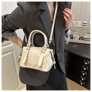 Detail of cream Boston bag with embossed logo texture and silver metal hardware