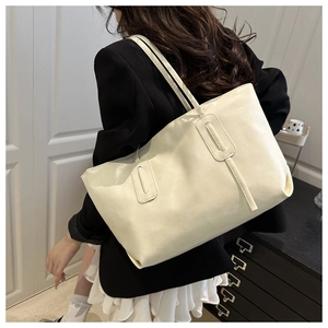 Rear view of a model carrying an off-white large tote bag with tassel detail and sleek finish