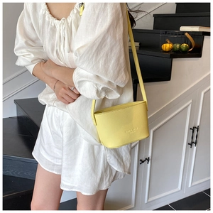 Close-up of yellow lychee pattern leather bucket bag with fine shoulder strap detail