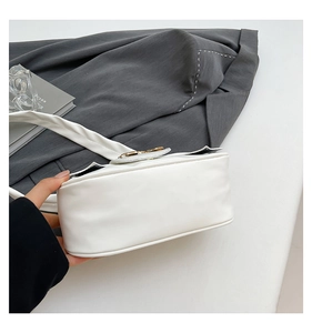 Detail view of the wide bottom and curved structure of this white pleated underarm bag