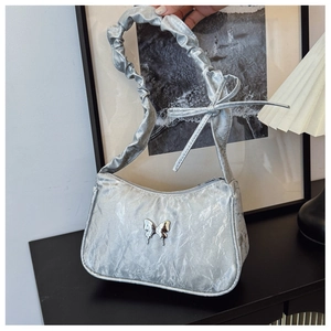 Detail of silver metallic ruched underarm bag with butterfly charm and pleated handle