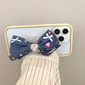 Detail of blue denim bow phone grip with pink heart rhinestone in Y2K style