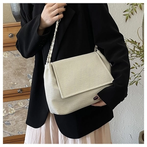 Detail of cream crossbody bag with textured twill fabric and metal chain strap
