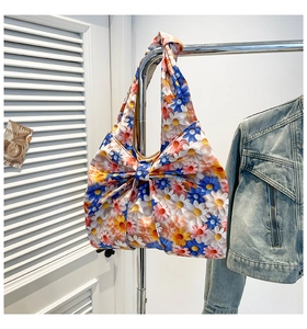 Detailed view of floral tote bag with a large bow hanging next to a denim jacket
