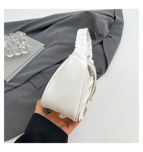 Detail of white pleated handle and golden metal buckle on stylish crescent underarm bag