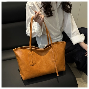 Close-up of caramel PU leather bucket bag with visible texture and long shoulder straps