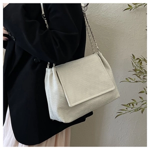 Detail of off-white textured shoulder bag with silver chain strap on model