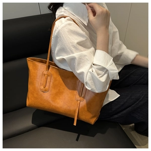 Brown vintage faux leather tote bag showcased on a sofa in a casual lifestyle setting