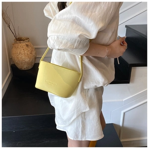 Detailed view of a yellow litchi pattern bucket bag featuring debossed fashion lettering