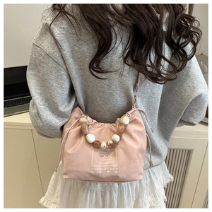 Detail of pink satin bucket bag with amber resin bead handle and bear graphic print