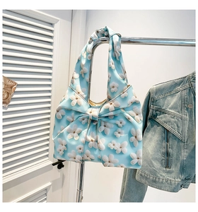 Detail of light blue floral shoulder bag with a large bow and white 3D flower patterns