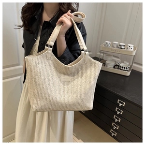 Detailed texture of beige woven straw tote bag featuring a stitched 'FASHION' leather patch