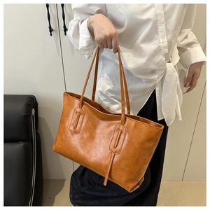 Brown faux leather tote bag held by model featuring vintage minimalist shoulder straps