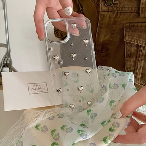 Détail d'une coque iPhone transparente avec cœurs 3D argentés et cadre photo métallique