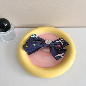 Detailed view of denim bow phone socket with pink heart rhinestone and colorful sequins
