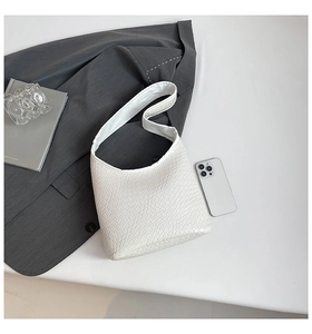 Detail of white crocodile embossed leather shoulder bag with wide strap on minimalist desk