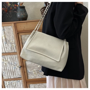 Detail of the cream textured fabric and woven silver chain strap on this shoulder bag