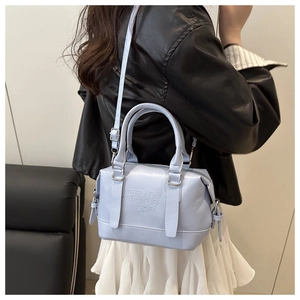 Sac boston bleu clair en similicuir avec lettres gaufrées porté par un mannequin