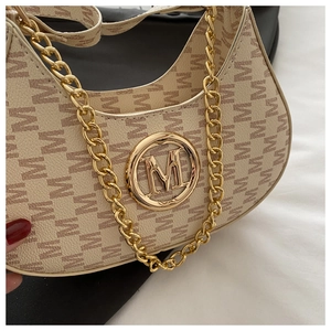 Detail of beige monogram print bag with gold M-logo hardware and chunky gold chain strap