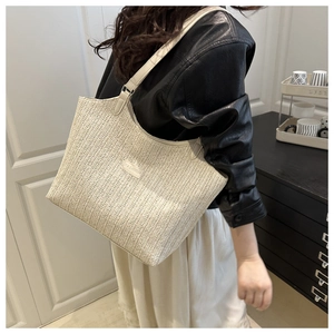 Close-up of beige woven tote bag with V-shaped straw texture and faux leather fashion label