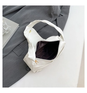 Detail view of white pleated handle handbag featuring gold zipper and dark brown lining